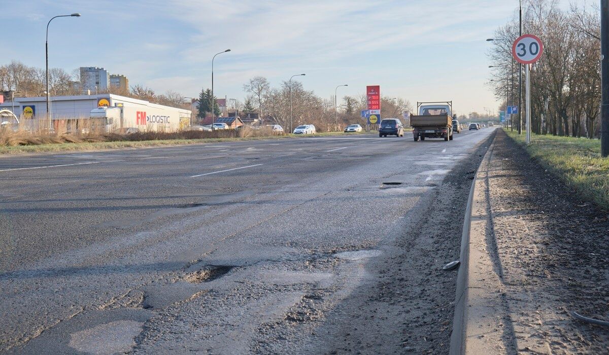 Widoczne ubytki w jezdni na al. Tysiąclecia, jeszcze przed znakiem 30 km/h