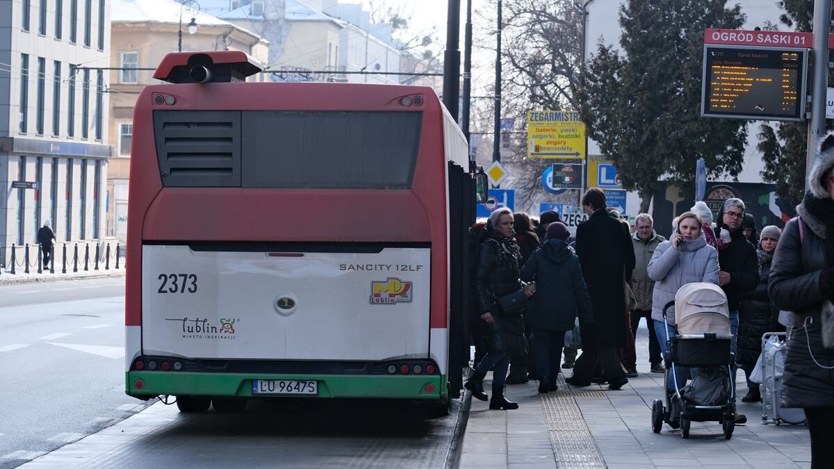 Pasażerowie wsiadający do autobusu na przystanku