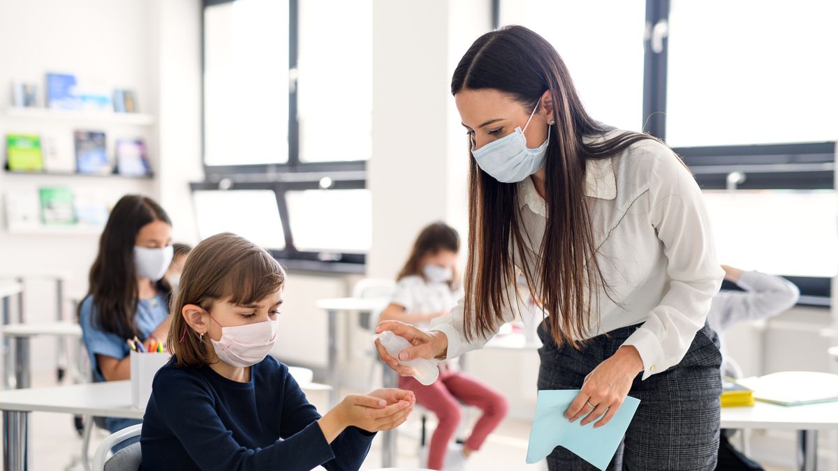 Nauczycielka spryskująca ręce uczennicy płynem do dezynfekcji