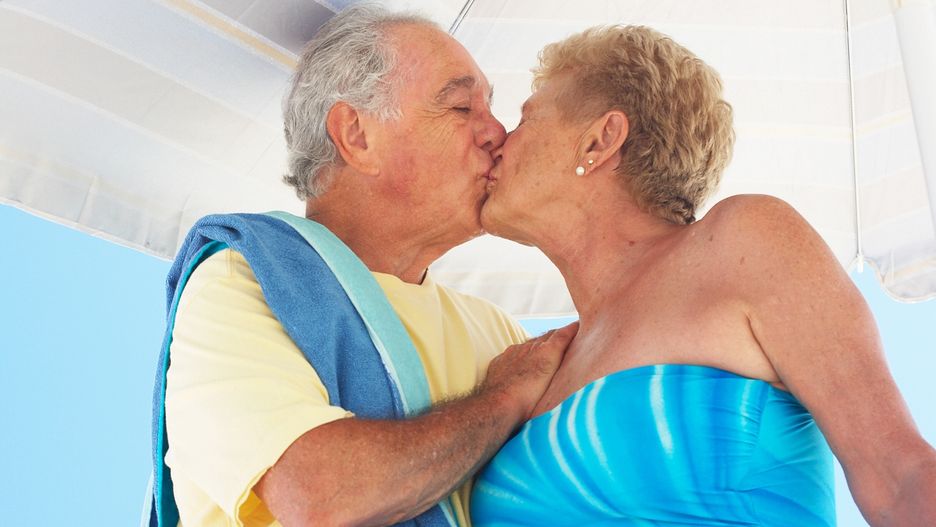 Senior couple kissing under beach umbrella, three quarter lengthChristopher RobbinsEasy Retouch, Colour, Photography, horizontal, outdoors, day, low angle view, three quarter length, embracing, standing, casual clothing, senior adult, 70-75 years, senior women, senior men, adults only, husband, wife, two people, couple, young at heart, retirement, active seniors, beach, one piece swimsuit, romance, affection, love, Caucasian, kissing, beach, umbrella, towel