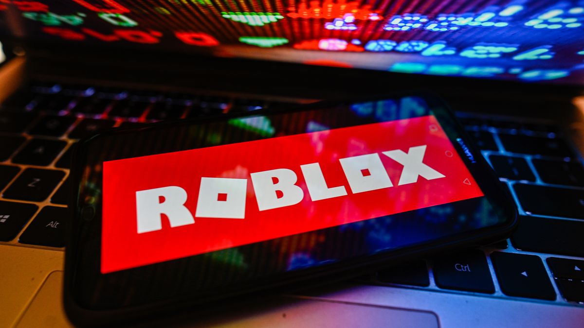 POLAND - 2023/11/09: In this photo illustration a Roblox logo is displayed on a smartphone with stock market percentages on a laptop. (Photo Illustration by Omar Marques/SOPA Images/LightRocket via Getty Images)