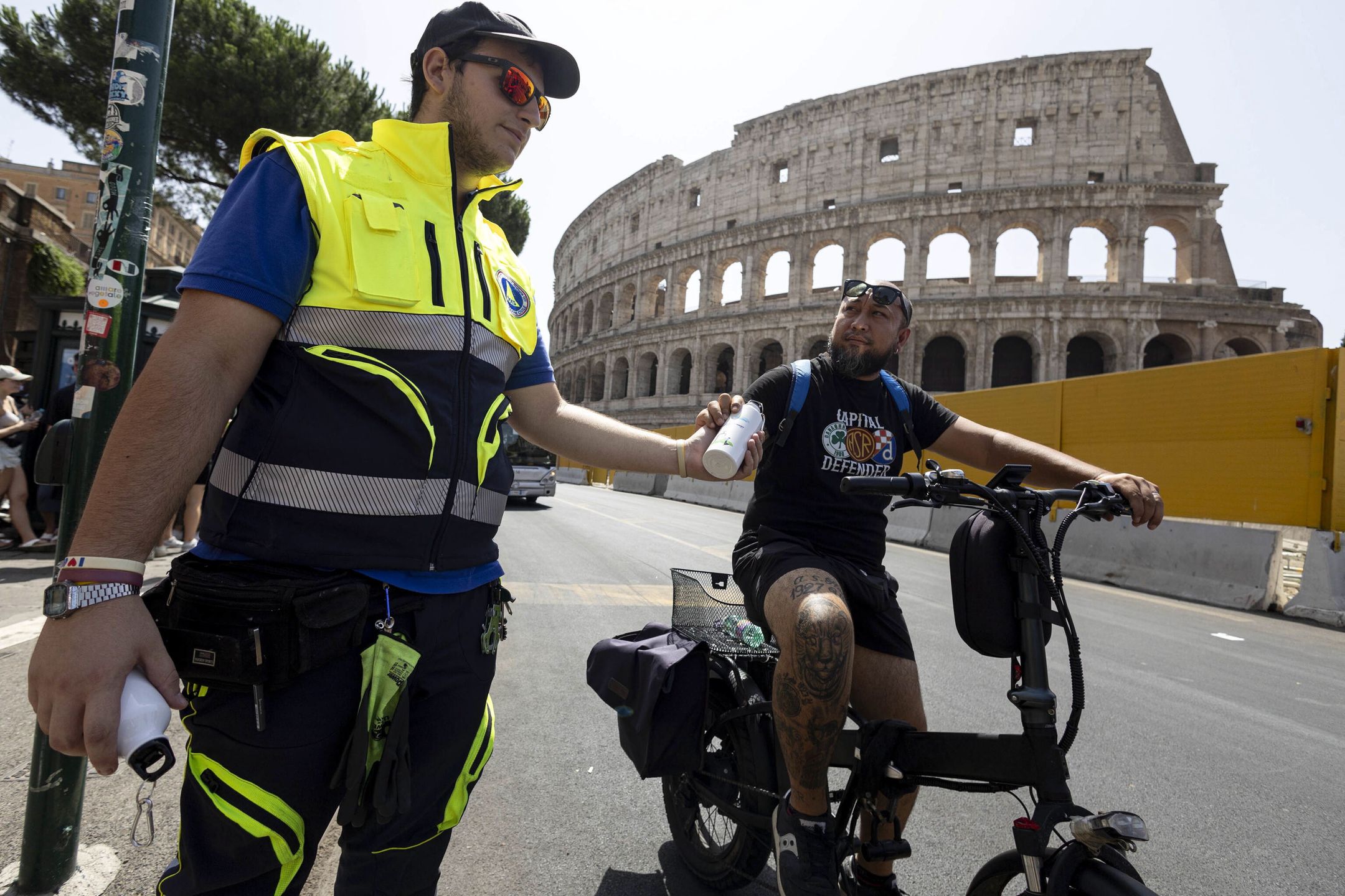 A Civil Protection officer (L) hands a bottle of water to a person near the Colosseum amid a heatwave and high temperatures, in Rome, Italy, 18 July 2023. Italy is facing the third heatwave of the summer on 18 July bringing record temperatures. The new heatwave is forecast to peak on 18 July, when temperatures in areas of southern Sardinian may reach 48 degrees Celsius, according to forecasts. On 15 July, the country's health ministry has put on red alert major Italian cities. EPA/MASSIMO PERCOSSI Dostawca: PAP/EPA.