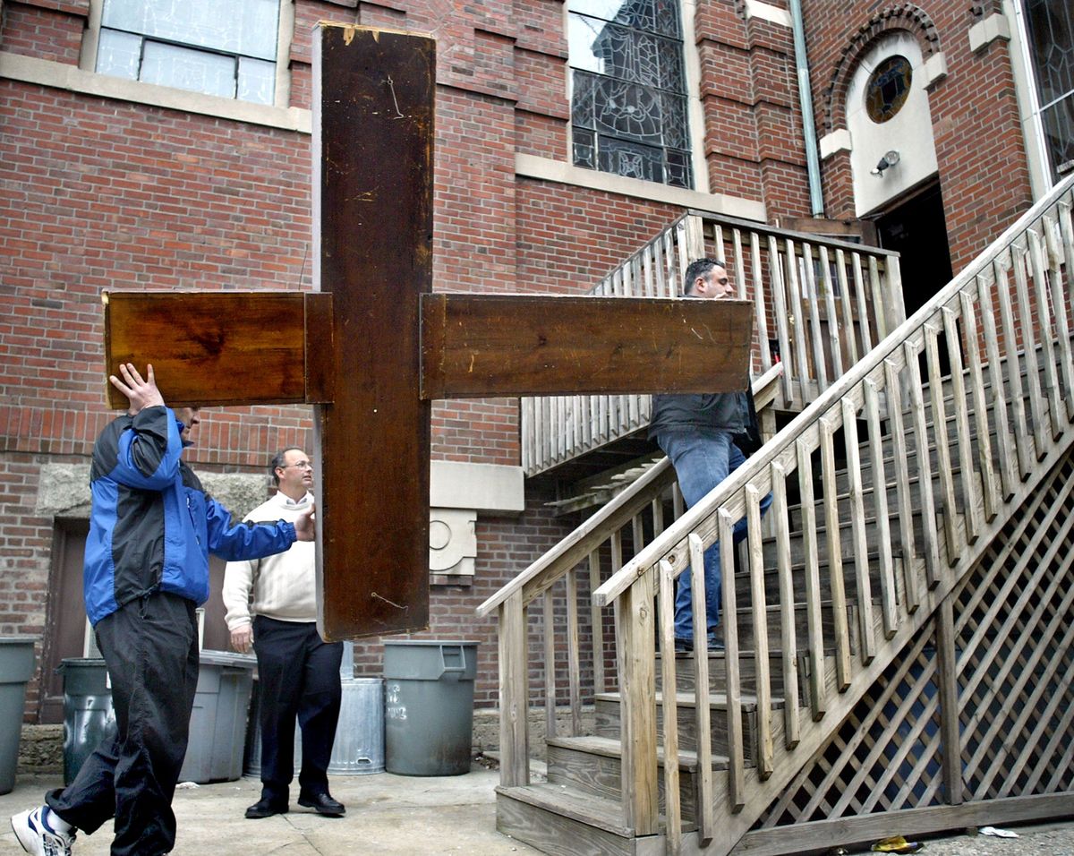 (03/23/2005 -East Boston, MA) Tradition continues.....At Our Lady Of Mount Carmel in Eastie a decades old cross is moved from the cellar to the pulpit ahead of tommorrow's Holy Thursday "Unofficial" Mass. The church has been closed for some time now and the parishioners are conducting services. This cross has been used for decades on Holy Thursday as candles are placed on it. LTOR Gene Schepici, Steve Ashcraft and Pasquale Capogreco.(032305churchmg-Staff Photo: Mark Garfinkel.saved phto1/wed) (Photo by Robert Eng/MediaNews Group/Boston Herald via Getty Images)