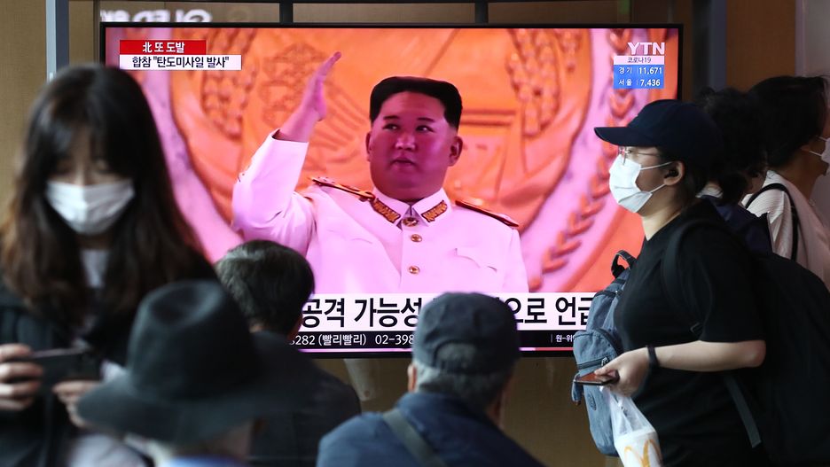 Kim Dzong Un z uniesioną ręką przemawia do widzów. 