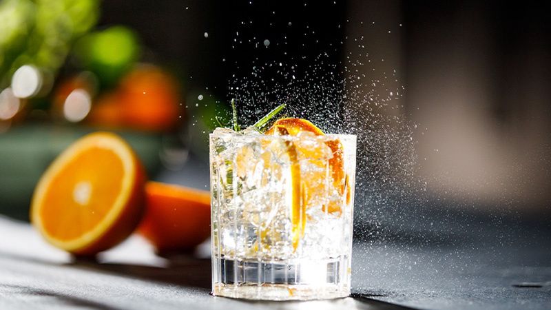Szklanka drinkówka z wodą gazowaną, lodem i pomarańczą