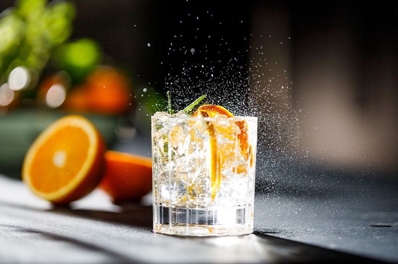 Szklanka drinkówka z wodą gazowaną, lodem i pomarańczą