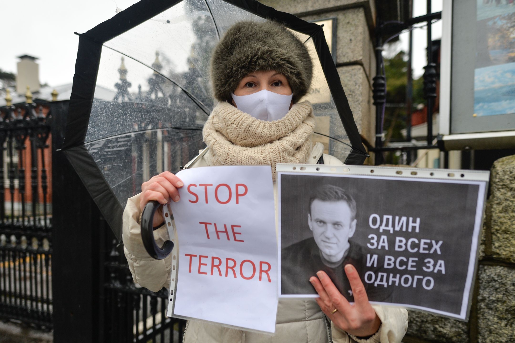 A protester wearing a face mask holds a 'One for All, All for One' and 'Stop The Terror' posters during a symbolic rally in support of the imprisoned Russian opposition leader Alexei Navalny in front of the Russian embassy in Dublin.On Sunday, 31 January, 2021, in Dublin, Ireland. (Photo by Artur Widak/NurPhoto via Getty Images)