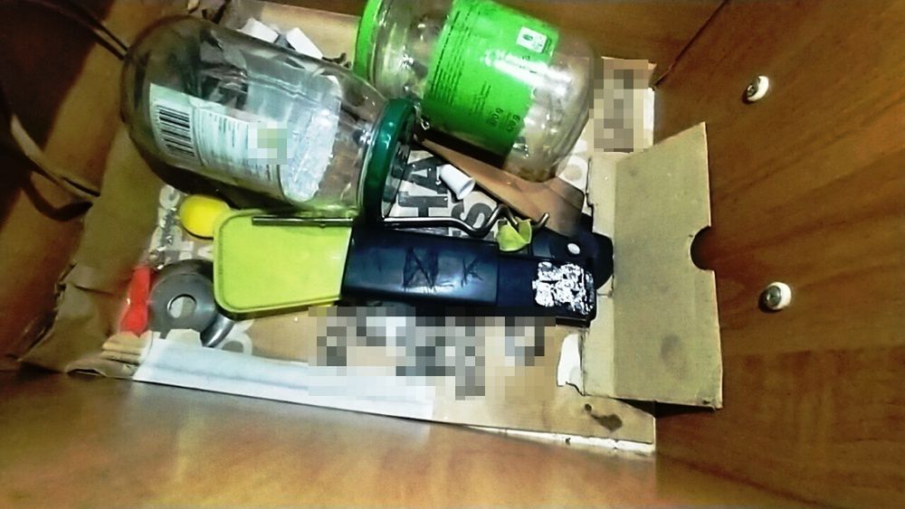 Zamknięta szuflada z różnymi przedmiotami, w tym słoikami, kluczykami i narzędziem do otwierania.