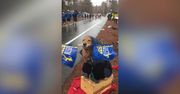 Czworonożny kibic na trasie maratonu. Uroczy golden retriever z flagą w pysku zagrzewał biegaczy do walki