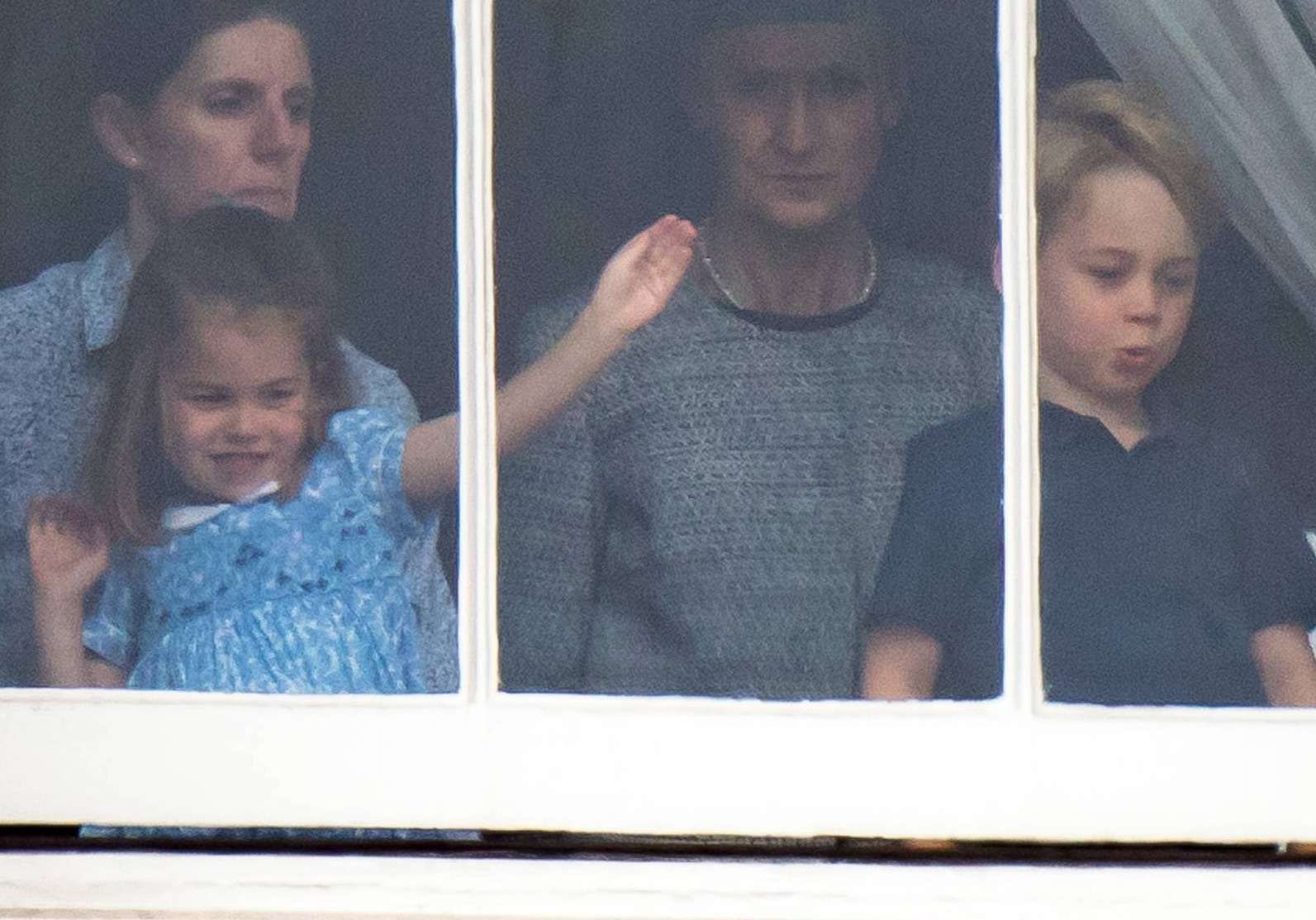 Księżniczka Charlotte i książę George stroją miny w oknie Pałacu Buckingham
