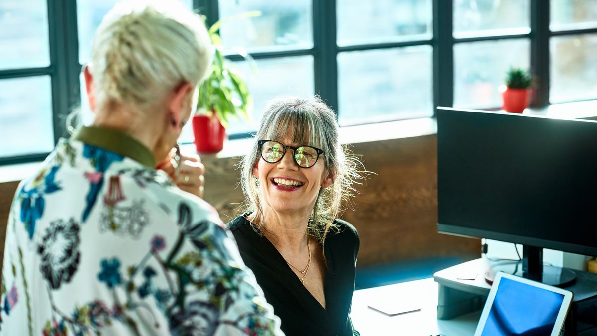 Cheerful mature woman at desk smiling towards senior female colleague
Two friends having conversation at work, woman in her 50s wearing glasses smiling and facing female manager, agreement, support, collaboration
10'000 Hours