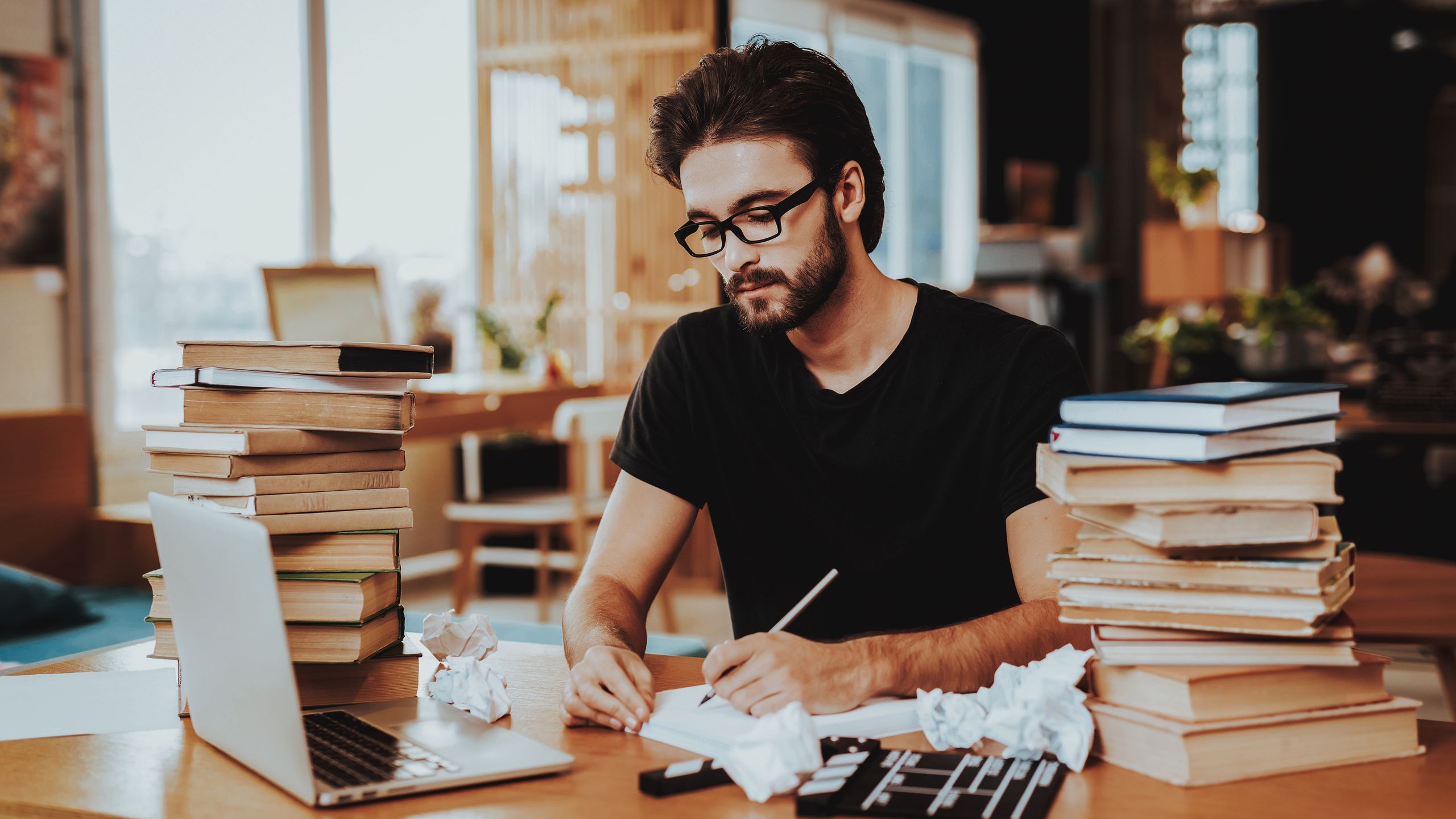 Pensive Freelance Text Writer Working at DeskPensive Freelance Text Writer Working at Desk. Pensive Handsome Hardworking Freelance Screenwriter Scenarist Sits Near Big Stacks of Books Writing Article, Novel, Play on Paper Sheets Looks Awayauthor, bearded, book, business, classic, concept, creative, freelancer, handsome, internet, desk, indoor, notebook, pile, portrait, reading, stack, books, literature, stress, novel, page, paper, poet, table, technology, text, type, typewriter, workplace, write, writer, work, writing, young, screenwriter, play, scenarist, nervous, laptop, man, person, ideas, freelance writer, paper sheets, text writer