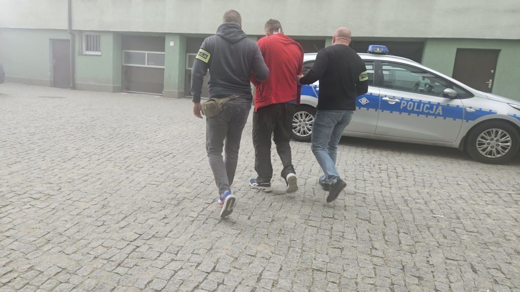 Zatrzymany mężczyzna w asyście funkcjonariuszy 