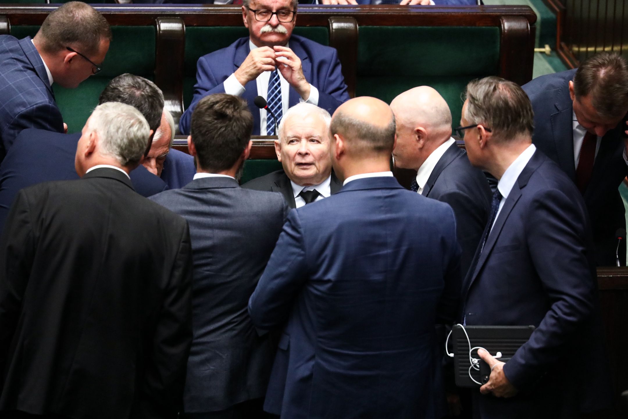 Na zdjęciu stojący posłowie PiS pochyleni nad siedzącym w ławie sejmowej Jarosławem Kaczyńskim