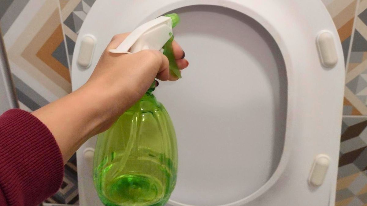 Kobieta spryskuje detergentem deskę sedesową