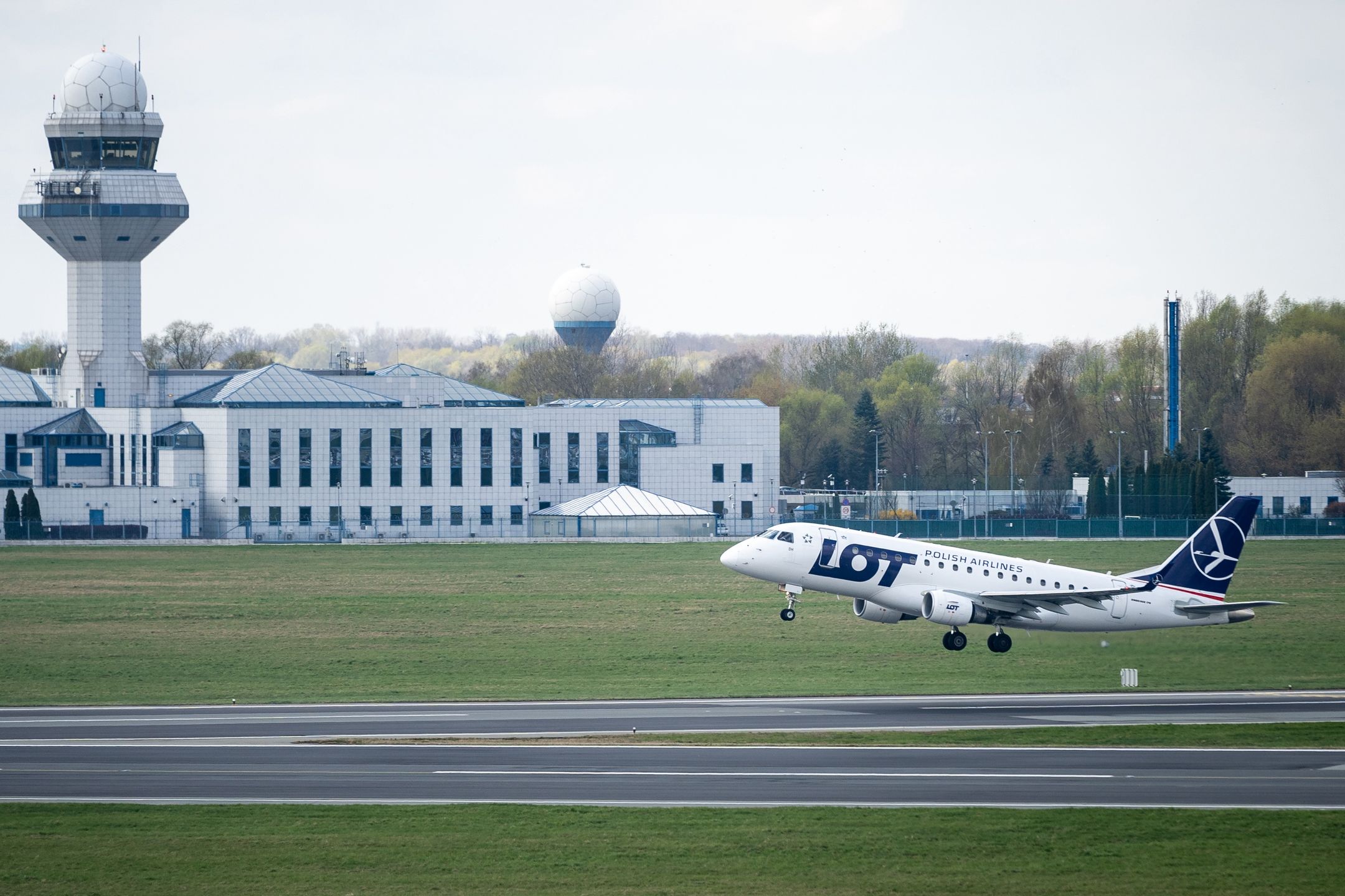 LOT Polish Airlines plane and Polish Air Navigation Services Agency (in background) at Chopin Airport in Warsaw, Poland on April 22, 2022. The strike and mass resignations of air traffic controllers from the Polish Air Navigation Services Agency result in many delays and canceled flights in Polish airspace. (Photo by Mateusz Wlodarczyk/NurPhoto via Getty Images)