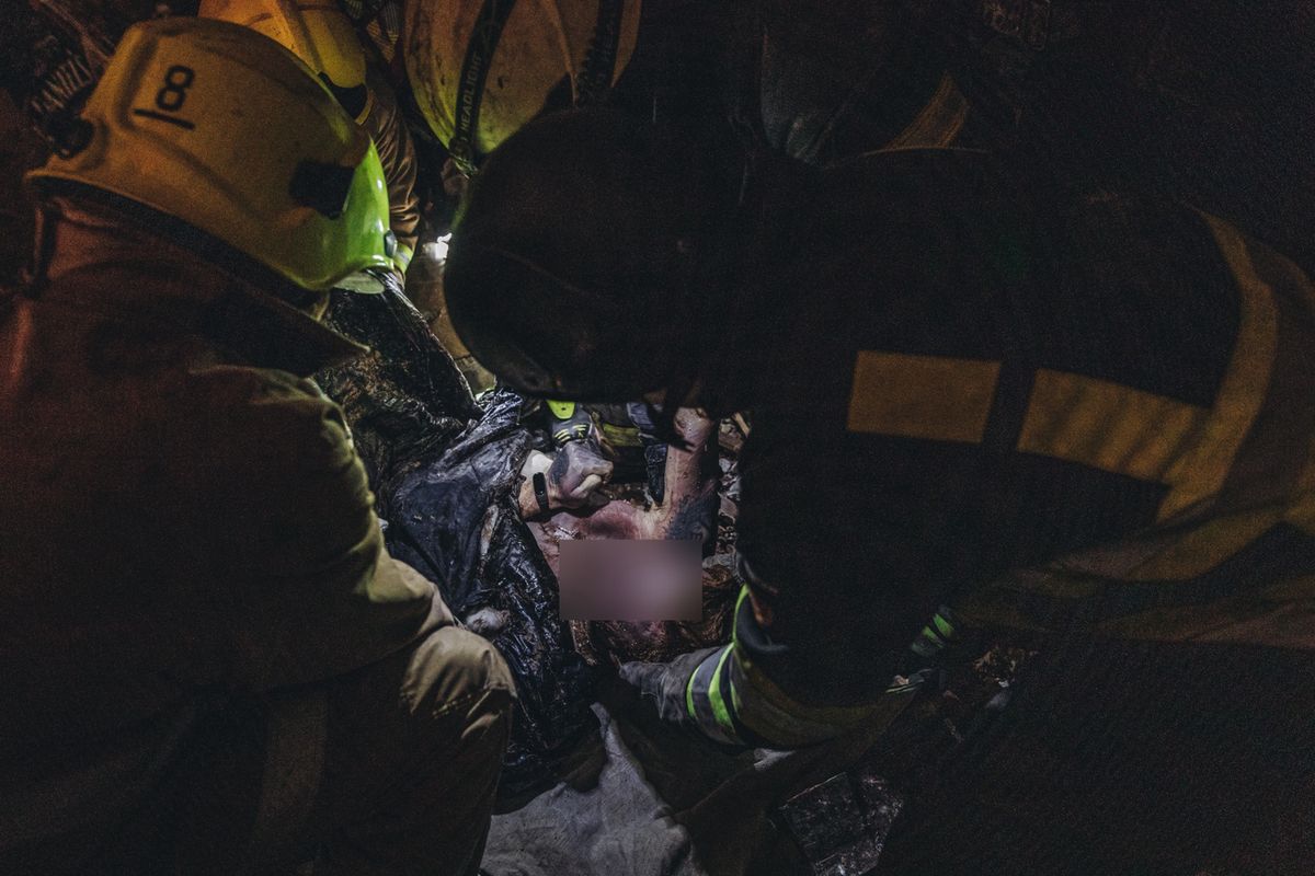 Strażacy wynoszą spod gruzów ciało żołnierza, który zginął w rosyjskim ostrzale Charkowa. 14.03.2022 r. 
