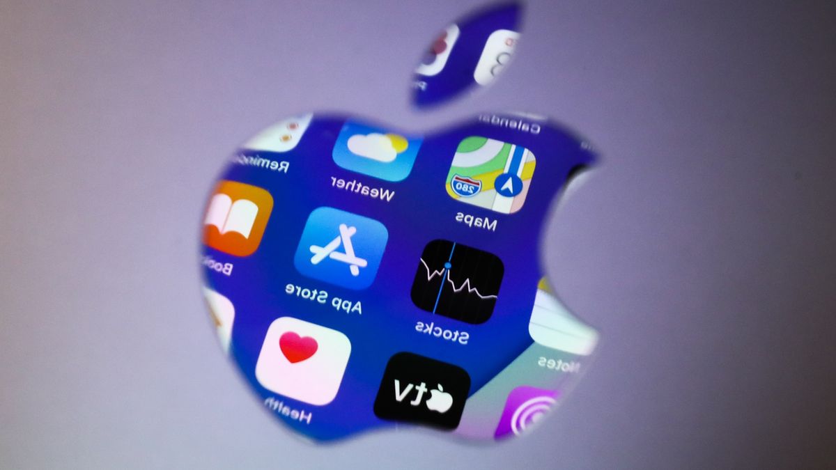 Icons displayed on iPhone screen are seen reflected in Apple logo on MacBook in this illustration photo taken in Krakow, Poland on April 13, 2022. (Photo Illustration by Jakub Porzycki/NurPhoto via Getty Images)