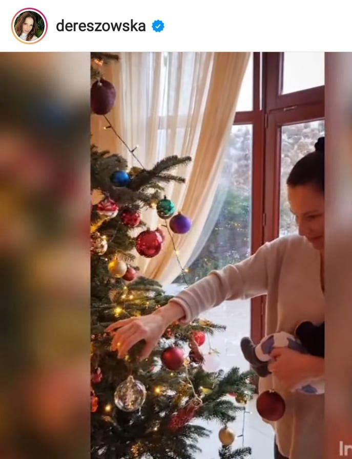 Anna Dereszowska z synkiem na rękach stroi choinkę