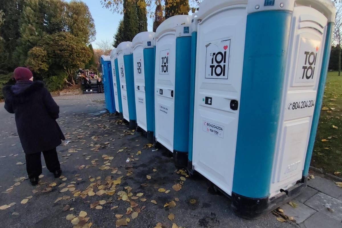 Ludzie oczekujący w kolejce do toi toi na cmentarzu na Majdanku