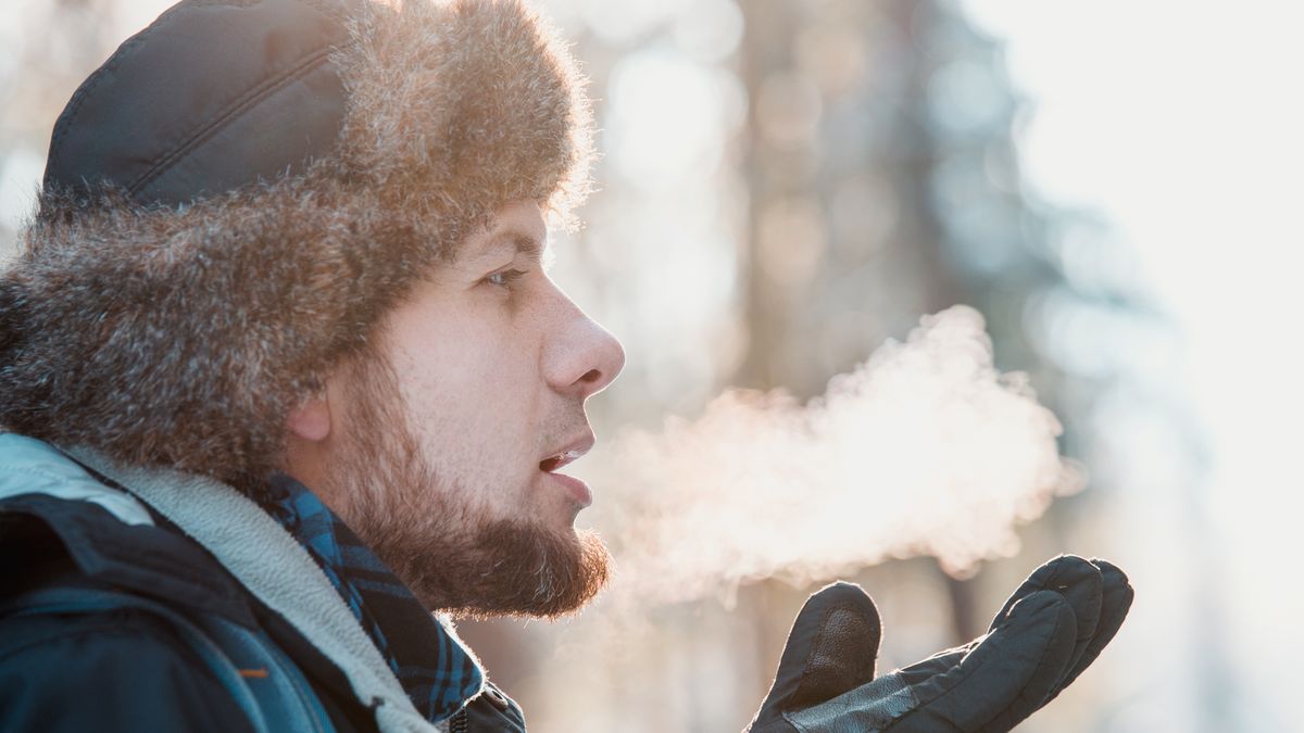 Na zdjęciu mężczyzna wydmuchujący powietrze na mrozie