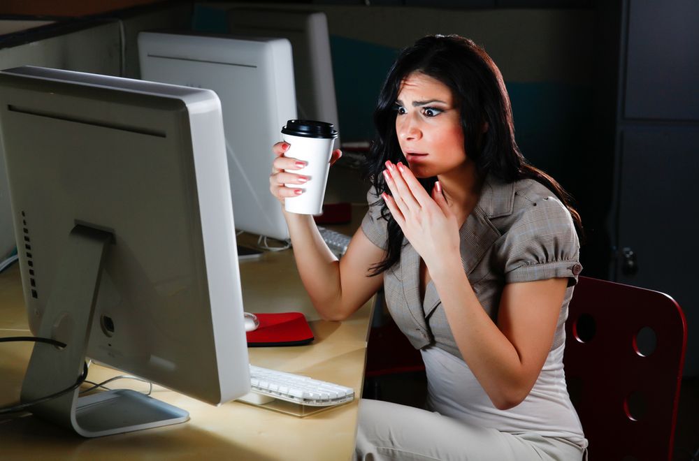 Zdjęcie Woman at computer looks shocked pochodzi z serwisu Shutterstock