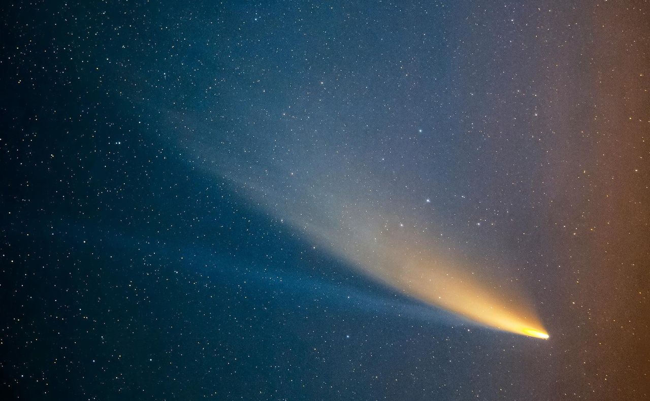 A comet with a visible yellow dust tail and a blue ion tail.