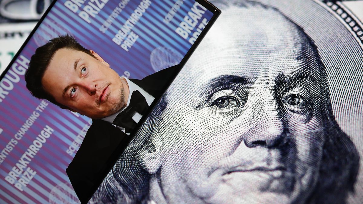 ANKARA, TURKIYE - OCTOBER 07: In this photo illustration, a portrait of the businessman Elon Musk is displayed on a mobile phone screen in front of a computer screen displaying one hundred dollars photo in Ankara, Turkiye on October 07, 2025. (Photo by Harun Ozalp/Anadolu via Getty Images)
