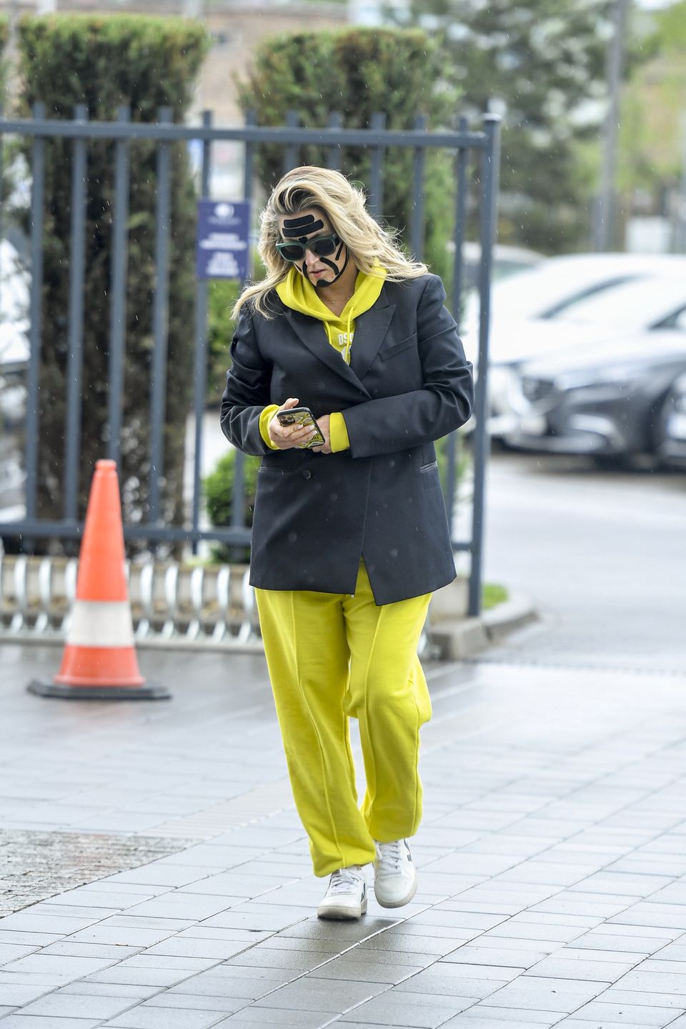 Karolina Szostak wpatrzona w telefon mknie do pracy z taśmami na twarzy 