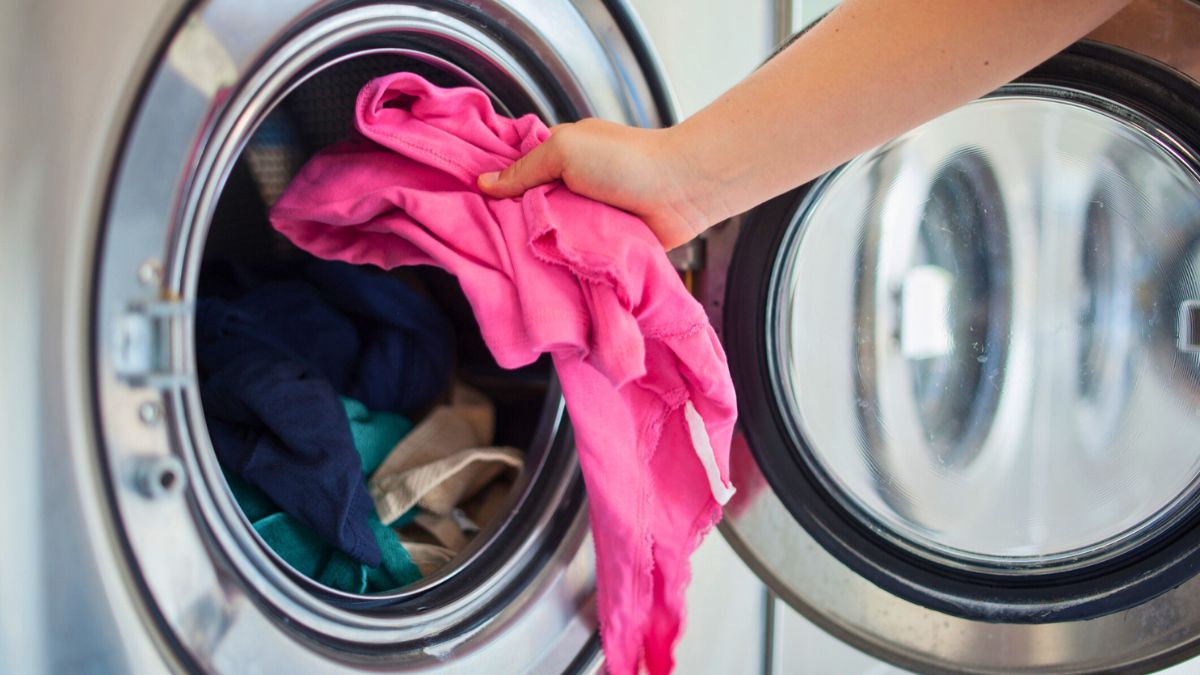 Kobieta wkłada ubrania do pralki