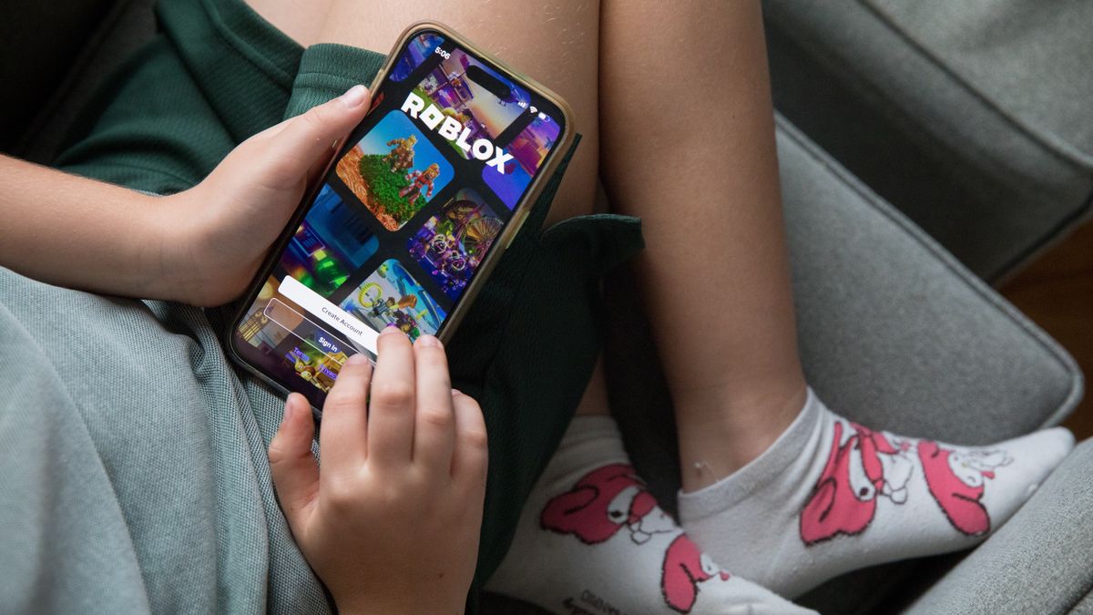 A child holds a smartphone displaying the Roblox app login page arranged in Sydney, Australia, on Wednesday Feb. 11, 2026. Australia's government ramped up pressure on Roblox Corp., summoning executives to explain reports that have alleged children as young as four years old have been sexually groomed on the gaming service. Photographer: Brent Lewin/Bloomberg via Getty Images