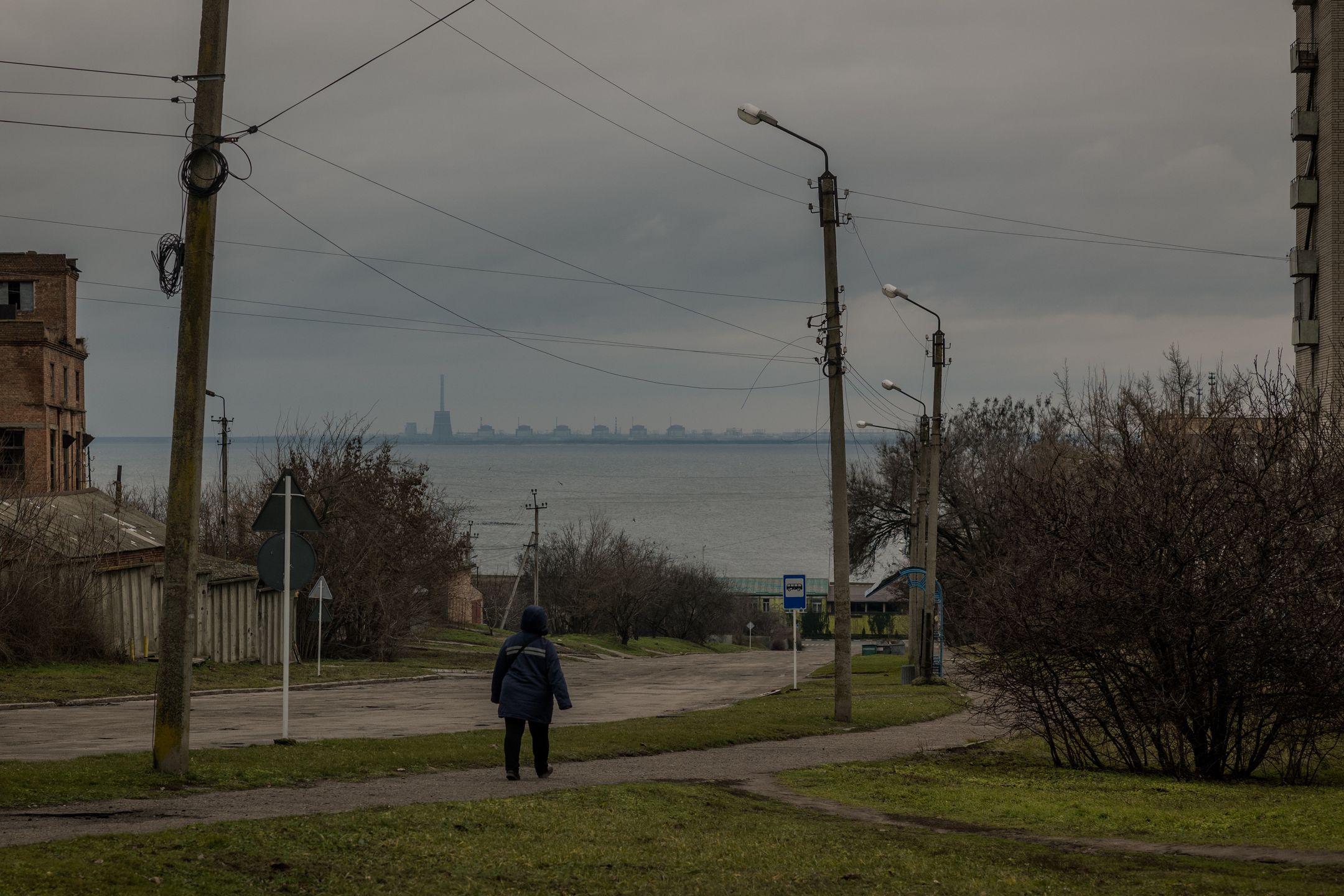 Kobieta idzie ulicą w Nikopolu. W tle widać Dniepr, a na jego drugim brzegu opanowaną przez Rosjan elektrownię atomową w Zaporożu. Nikopol jest regularnie ostrzeliwany przez rosyjskie wojska. Od początku wojny w mieście zginęły 34 osoby, a 150 zostało rannych. Mimo wojny i ciągłego zagrożenia miasto próbuje normalnie żyć. Otwarte są sklepy i kawiarnie, jeżdżą autobusy. Ale według szacunków władz w mieście pozostało zaledwie 30 proc. ze 130 tysięcy mieszkańców