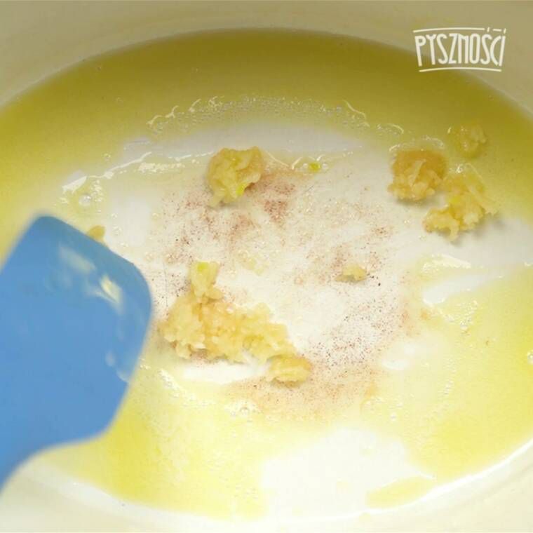 Na blacie kuchennym ułóż kuchenkę, po czym bezpośrednio na palniku ustaw duży garnek. Na początek rozpuść w garnku dwie łyżki masła. Kiedy produkt się roztopi, dodaj do garnka 2 ząbki czosnku. Wcześniej go obierz i przeciśnij przez praskę. Możesz również pociąć czosnek w drobne plasterki. Jako kolejne składniki dodaj do garnka bulion warzywny. Jeśli chcesz go przygotować samodzielnie, mamy sprawdzony przepis. Możesz również wykorzystać gotowy produkt ze sklepu. W garnku powinno znaleźć się również mleko. Po wymieszaniu dodaj do naczynia surowy makaron, po czym gotuj ok. 25 minut. Pamiętaj, aby gotującą się mieszankę od czasu do czasu przemieszać przy pomocy kuchennej łyżki.
