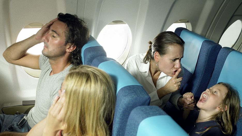 Girl yelling behind young couple in airplane

