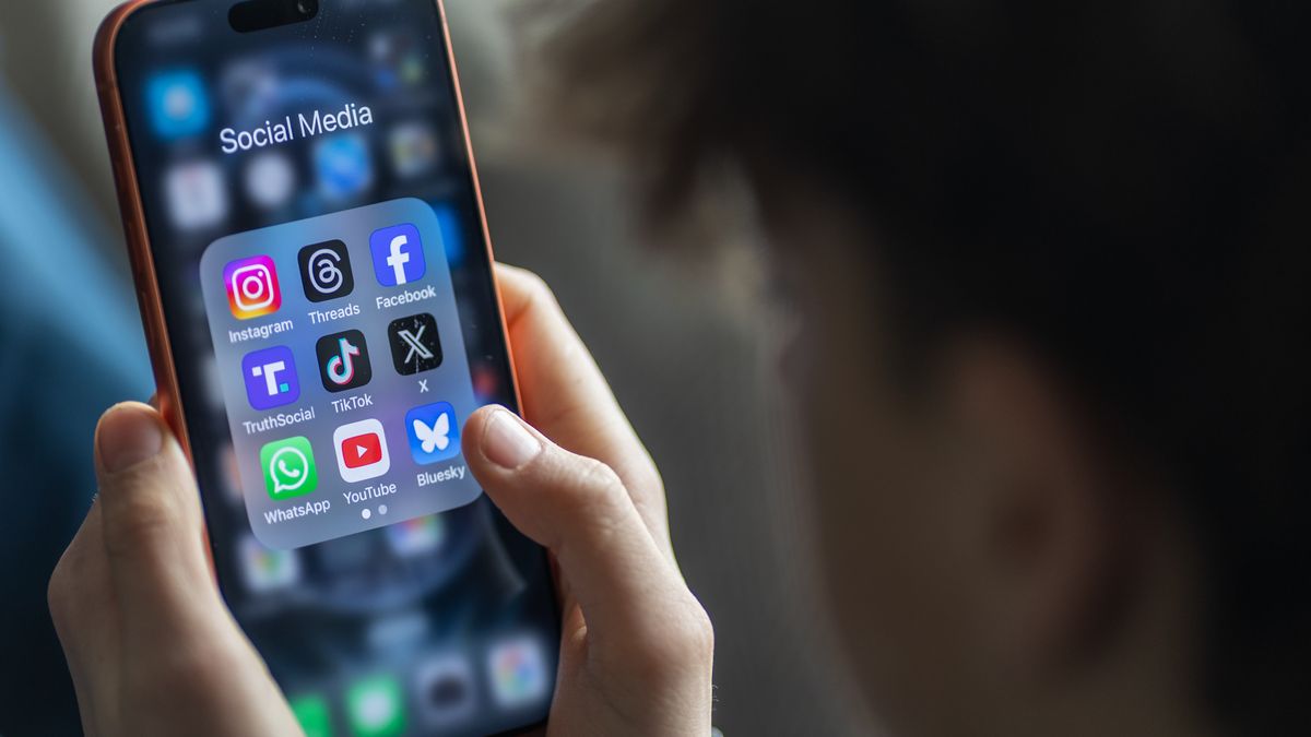BATH, UNITED KINGDOM - MARCH 29: In this photo illustration a 14-year-old boy holds an iPhone screen displaying various social media and messaging apps on March 29, 2026 in Bath, England. On top row left to right, the logo of social media platform Instagram is seen beside that of Meta’s Threads and Facebook. On the middle row from left is the logo of Donald Trump's Truth Social app, next to the logo of social media app TikTok and the logo of Elon Musk’s US online social media and social networking site 'X' (formerly known as Twitter). Along the bottom row, left to right is the messaging service WhatsApp, the logo for online video sharing and social media platform YouTube and the logo for the Bluesky app. In the UK, a ban on social media for under-16s has been backed by the House of Lords following the Australian law which aims to stop children under 16 from having social media accounts and social media platforms, including TikTok, Facebook, Snapchat, Reddit, X, formerly Twitter, and Instagram potentially being be fined for preventing children younger than 16 from having social media accounts. (Photo by Anna Barclay/Getty Images)