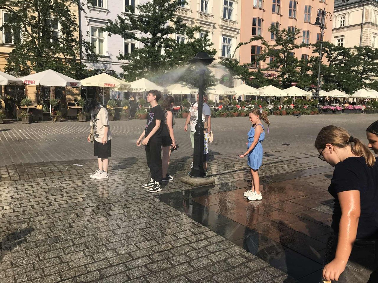 Kraków: Upał rozlewa się po mieście. Zraszacz na Rynku Głównym przyciąga spragnionych ochłody