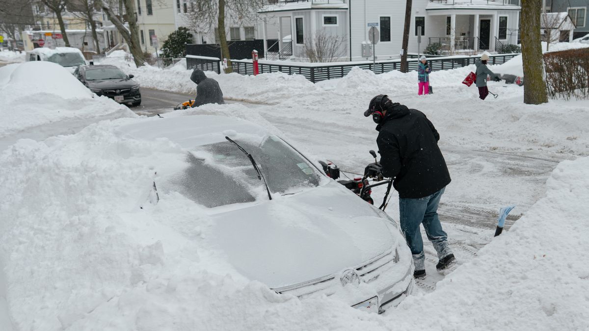 A resident clears snow surrounding a vehicle in Somerville, Massachusetts, US, on Monday, Jan. 26, 2026. US power grids are expected to grapple with unprecedented seasonal demand and the threat of blackouts after a damaging winter storm coated parts of the South and Mid-Atlantic in ice - leaving brutal cold in its wake. Photographer: Mel Musto/Bloomberg via Getty Images