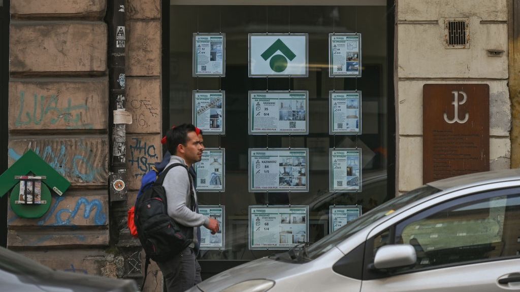 Na zdjęciu ludzie mijający agencję nieruchomości