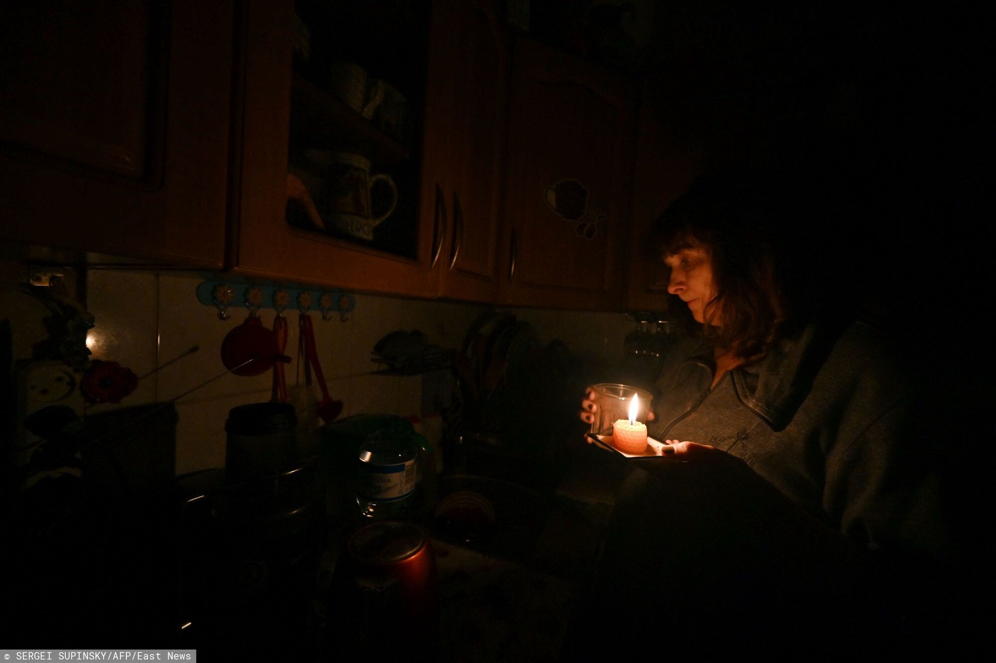 Blackout w KijowieThis photograph taken on November 5, 2022, shows Iren Rozdobudko, a 60-year-old writer and lecturer at the university, cooking and cleaning in her kitchen by candlelight during a power cut in the building in the north of the Ukrainian capital of Kyiv. - Since October 10, the Ukrainian electrical system has been heavily affected by multiple Russian strikes that have targeted the energy infrastructure. In order to avoid a total blackout, the national operator Ukrenergo has implemented scheduled power cuts in the capital as well as in many cities and regions of Ukraine. (Photo by Sergei SUPINSKY / AFP)SERGEI SUPINSKY