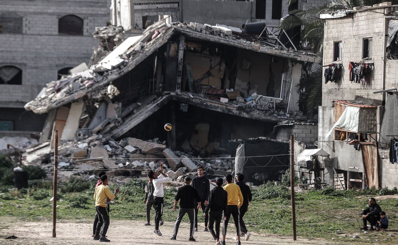 DEIR AL-BALAH, GAZA - MARCH 27: Palestinian youths, who take refuge in Nuseirat camp from ongoing Israeli attacks, pass the time by playing volleyball near a partially collapsed building while waiting for iftar time on the Holy month of Ramadan in Deir al-Balah, Gaza on March 27, 2024. (Photo by Ali Jadallah/Anadolu via Getty Images)