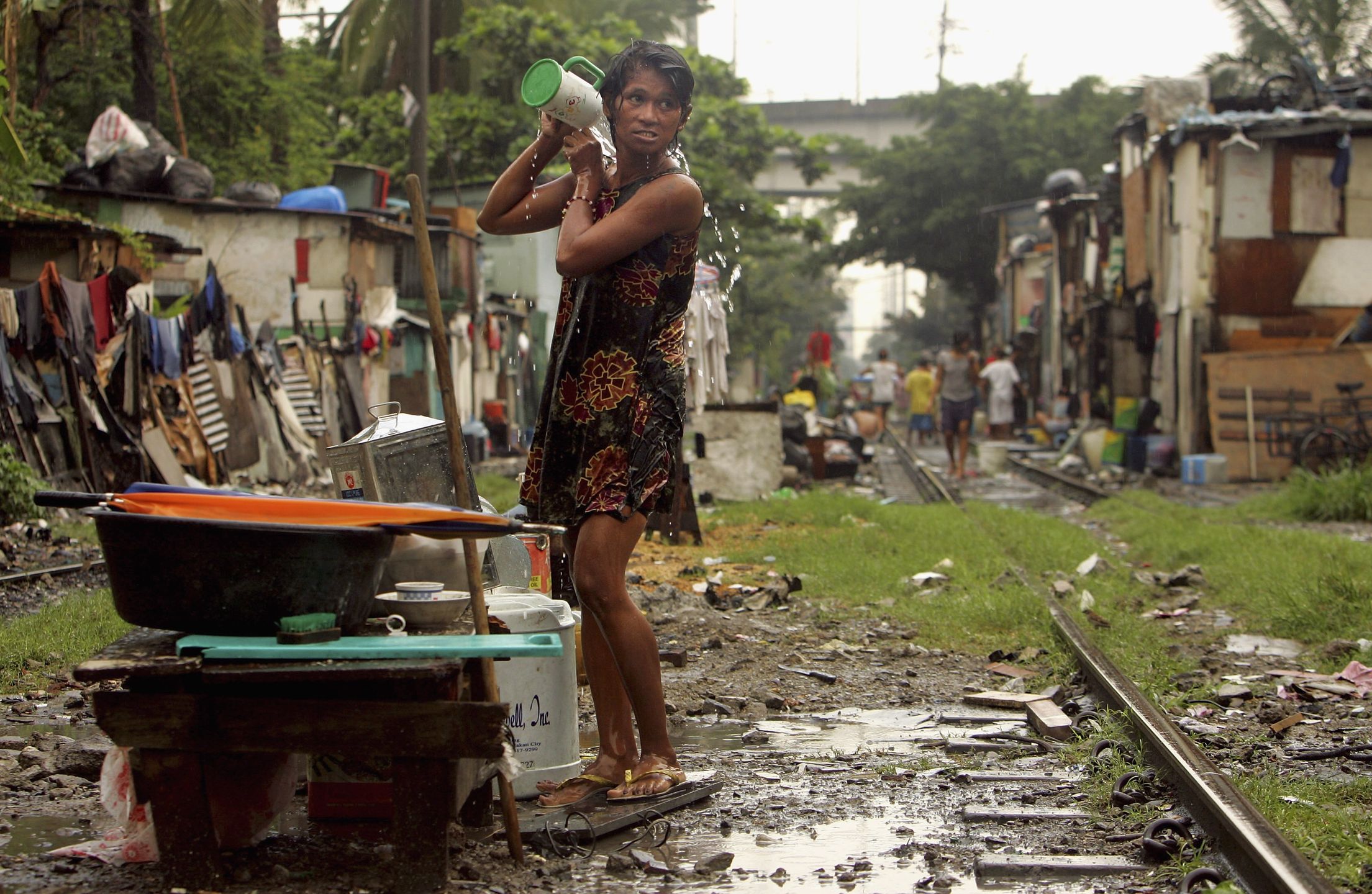 Poverty, Corruption, Unemployment and Overpopulation Help Cause Instability In PhilippinesMANILA, PHILIPPINES - JULY 14: A Filipino woman bathes along the railroad tracks where hundreds of poverty stricken live in the slums on July 14, 2005 in Manila, Philippines. Extreme poverty is commonplace in Manila where corruption, unemployment, and overpopulation are aided by a government policy against birth control pills and condoms. Many are calling for Philippines President Gloria Macapagal Arroyo to resign since she has been attacked by an election scandal leaving her political future in turmoil. Today she named a new Budget Chief to her staff after many had resigned last week.  (Photo by Paula Bronstein/Getty Images)Paula BronsteinPresident Gloria Macapagal Arro overpopulation unemployment pove
