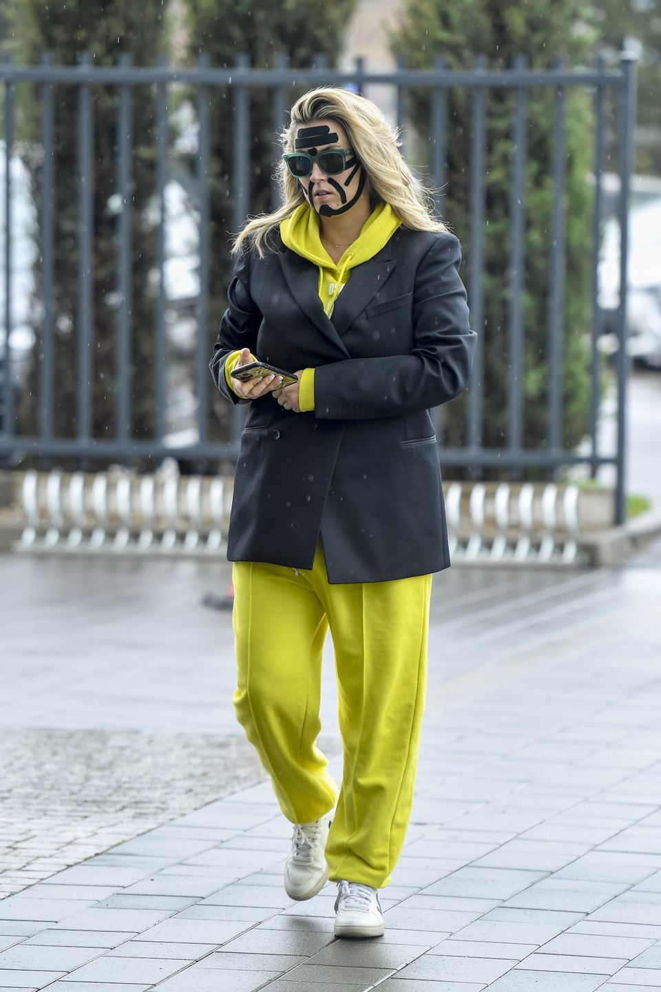 Karolina Szostak wpatrzona w telefon mknie do pracy z taśmami na twarzy 