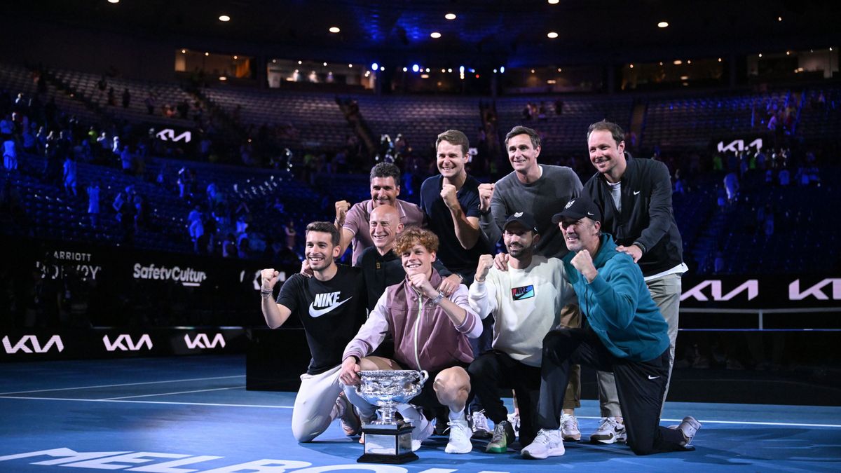 Jannik Sinner (w dolnym rzędzie z pucharem) wraz z członkami swojego sztabu cieszy się po triumfie w Australian Open 2024