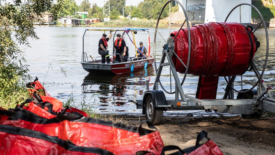 Szczecin, 17.08.2022. Strażacy stawiają zaporę elastyczną mającą za zadanie wyłapywanie śniętych ryb na Odrze w dzielnicy Szczecin Dziewoklicz