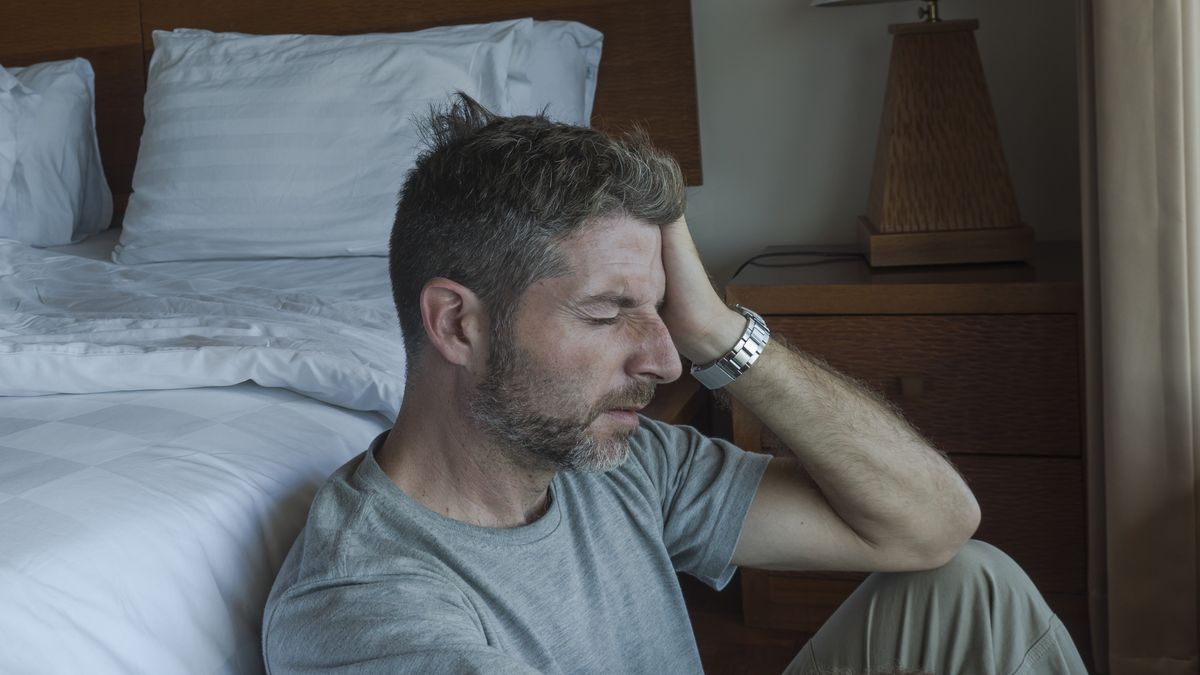 dramatic home portrait of young depressed and desperate man sitting on bedroom floor next to bed suffering depression and anxiety feeling overwhelmed and helplessdramatic home portrait of young depressed and desperate man sitting on bedroom floor next to bed suffering depression and anxiety feeling overwhelmed and helplessMarcos Calvo