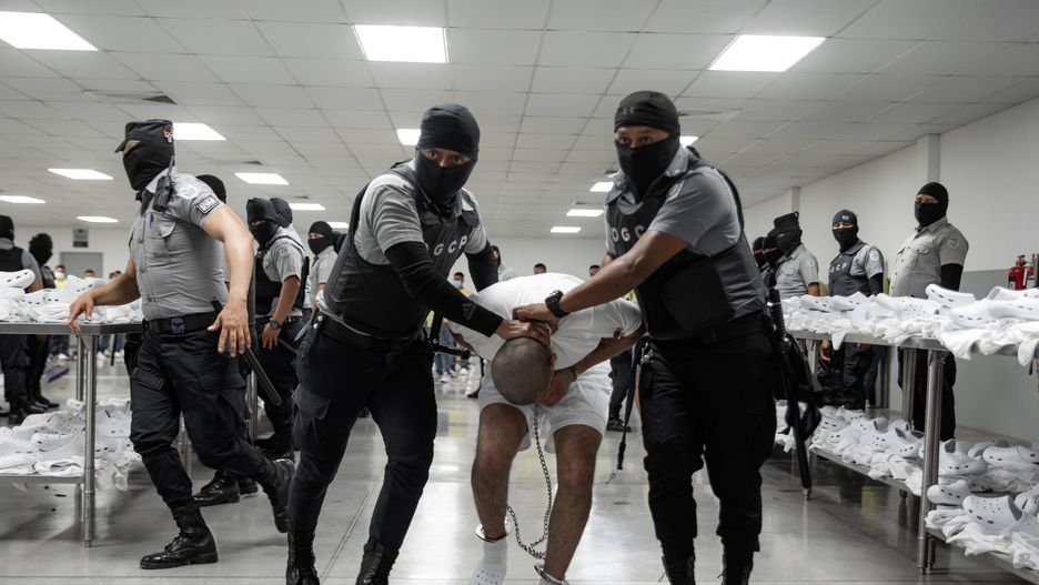 TECOLUCA, EL SALVADOR - MARCH 16: In this handout photo provided by the Salvadoran government,  guards escort a newly admitted inmate allegedly linked to criminal organizations at CECOT on March 16, 2025 in Tecoluca, El Salvador. Trump's administration deported 238 alleged members of the Venezuelan criminal organizations 'Tren De Aragua' and Mara Salvatrucha with only 23 being members of the Mara. Nayib Bukele president of El Salvador announced that his government will receive the alleged members of the gang to be taken to CECOT. On February of 2023 El Salvador inaugurated Latin America's largest prison as part of President Nayib Bukele's plan to fight gangs. (Photo by Salvadoran Government via Getty Images)