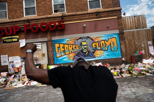 Mężczyzna klęczy przed muralem upamiętniającym George'a Floyda nieopodal miejsca, w którym zmarł.
