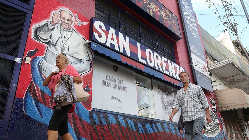 Na zdjęciu budynek w barwach klubu San Lorenzo i mural przedstawiający papieża Franciszka I, przed nim przechodnie
