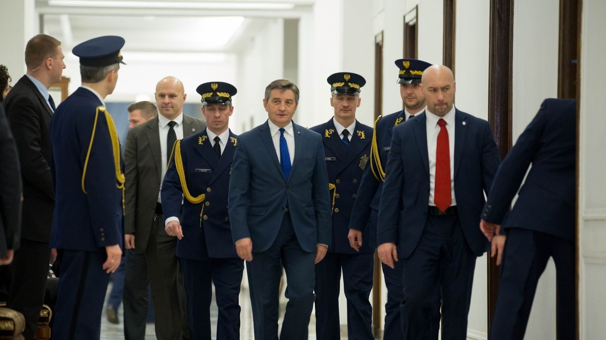 Marszałek Sejmu Marek Kuchciński w otoczeniu funkcjonariuszy Straży Marszałkowskiej.