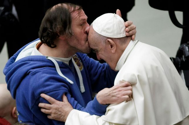 Papież Franciszek wycałowany przez wiernego podczas audiencji. 